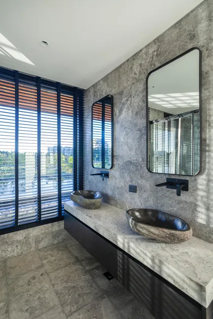 baño moderno con bachas de piedra natural y ventanales amplios — proyecto Muelles - Estudio Pacifica, por ABEJA CONCEPT, en Nordelta
